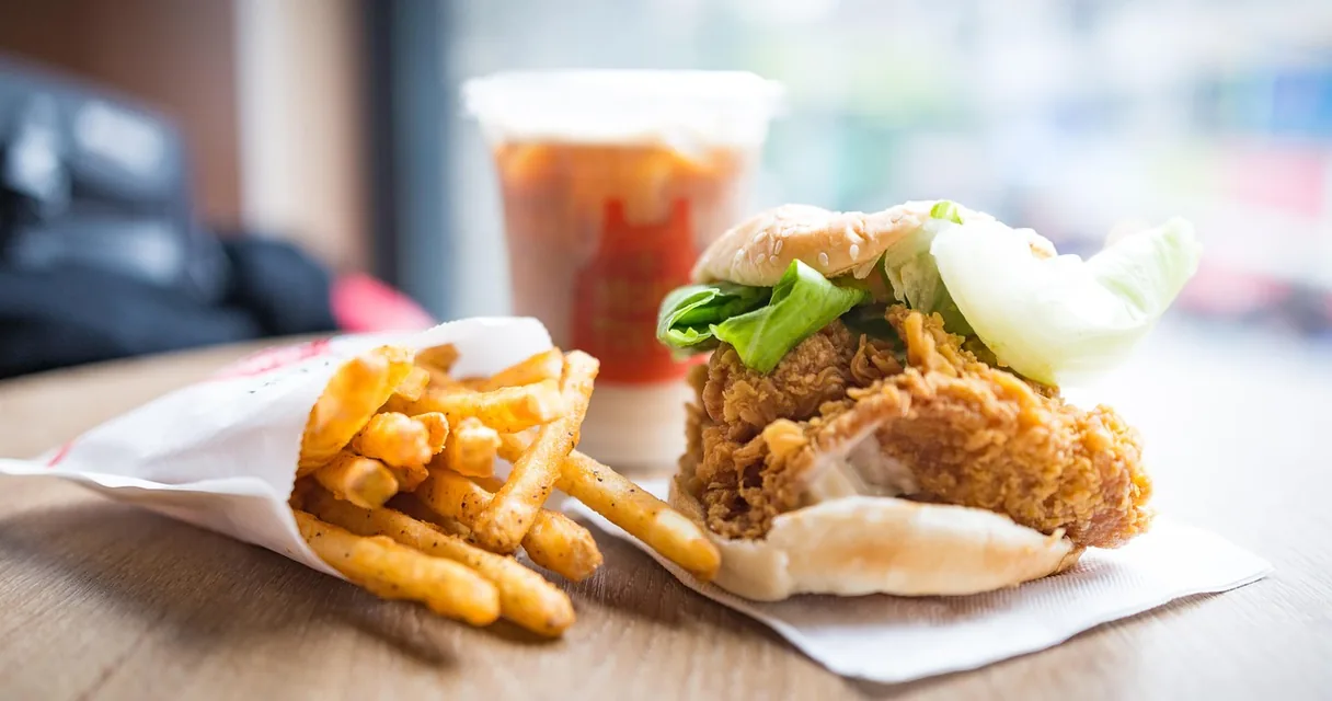 Sanduíche de frango frito, batatas fritas e refrigerante sobre a mesa de uma lanchonete